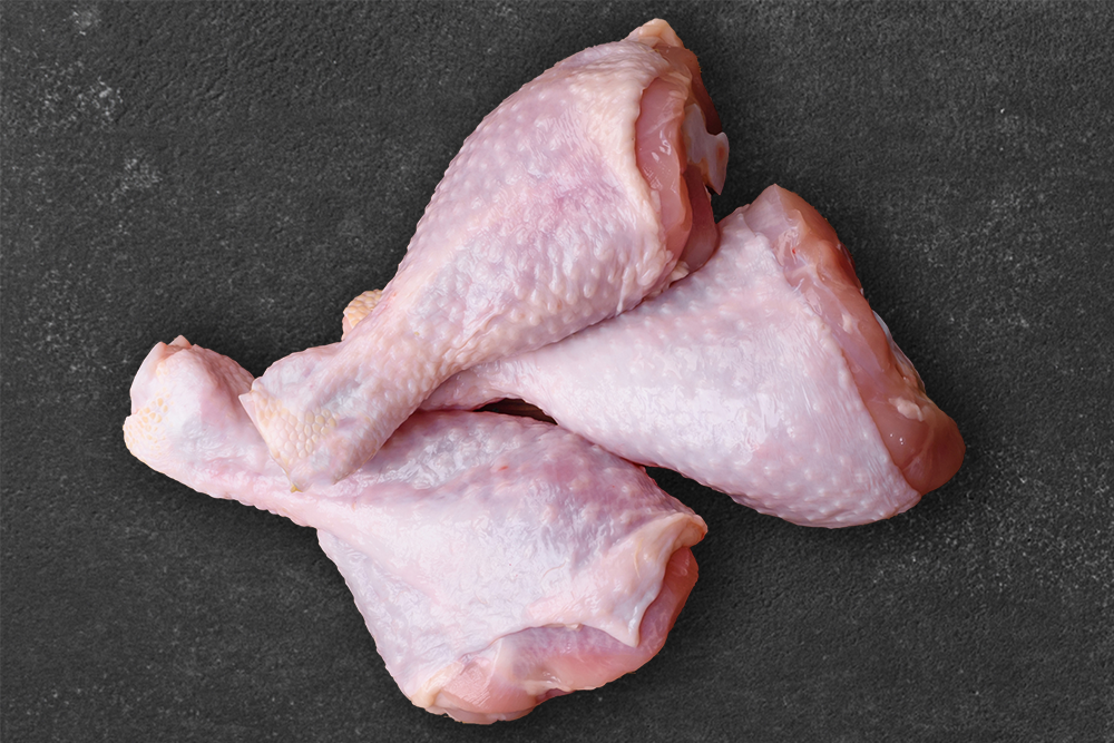 Raw chicken leg pieces are placed on a black background